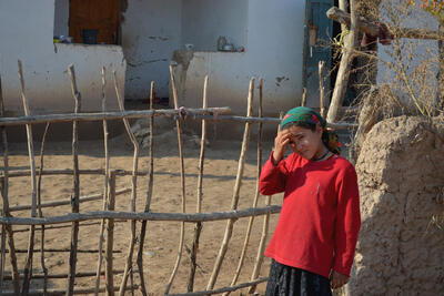 A young girl stands in front of her house