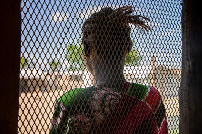 A women looks out of a window with a mesh.