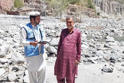 Ali Jabbar (right), whose agricultural land in Pakistan’s Khyber Pakhtunkhwa Province was devastated by flash floods in April 2024, shares his story of loss with UNA-UK staff member Umer Dil. Thousands of people have been affected by the floods that washed away farms, 80 canals and hundreds of fruit plants. Photo: UNA-UK