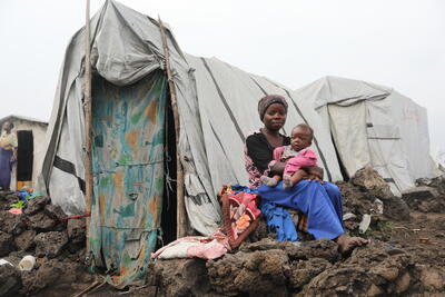 A mother and her child sit outside their makeshift shelter at the Lushagala displacement site in Goma, North Kivu, Democratic Republic of the Congo. 