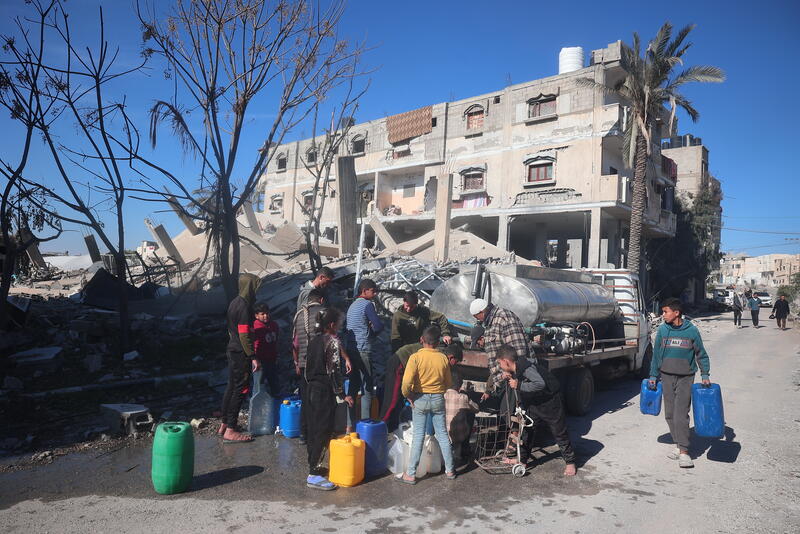 People gather around a water truck in Rafah to collect clean water. 